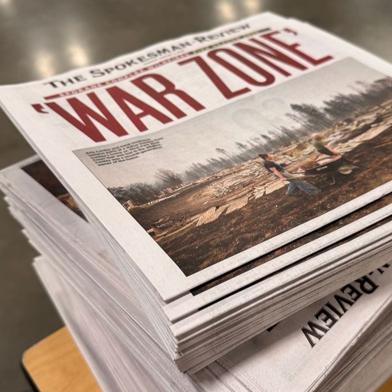 A stack of newspapers with the title "War Zone".