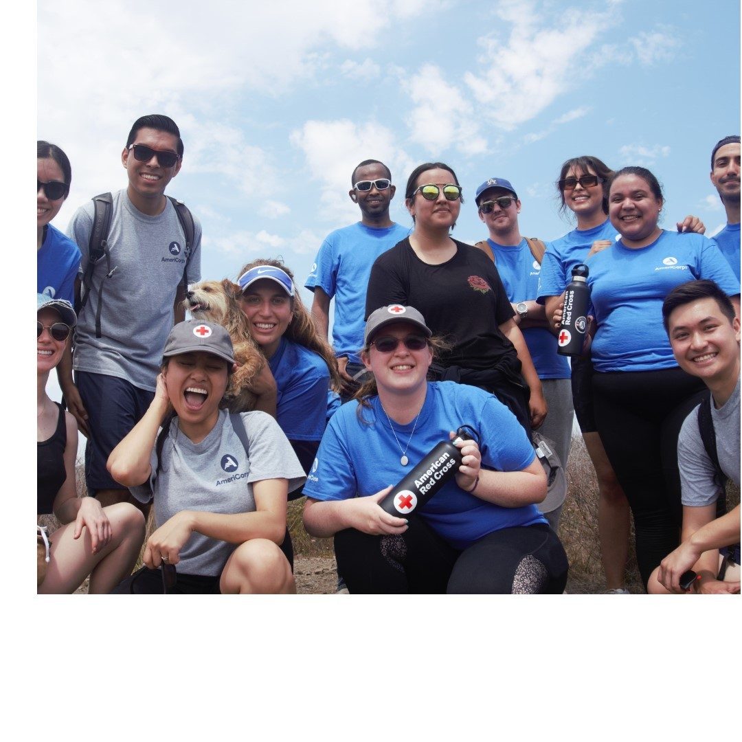 A group of people posing for a photo holidng red cross water bottles