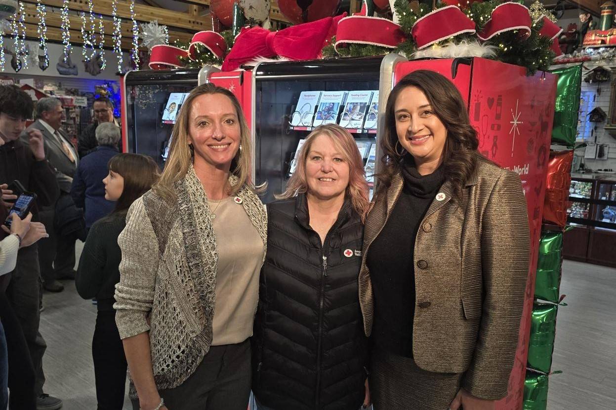 Three women stand in front of holiday gathering