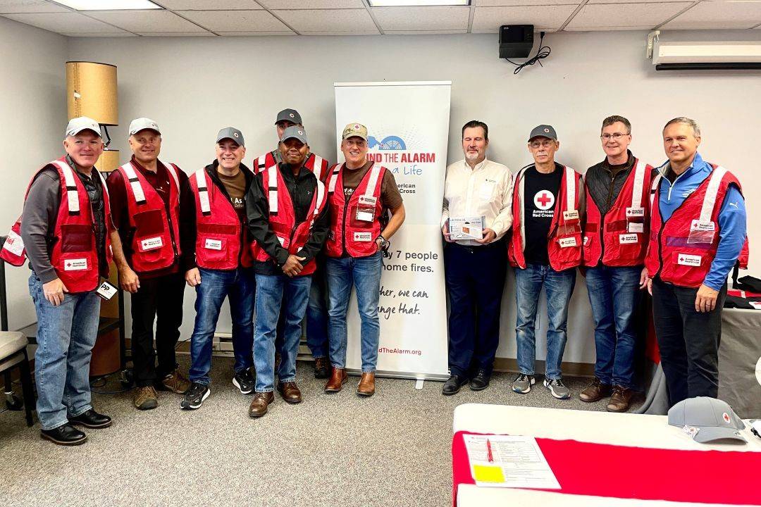 Group of Red Cross volunteers stand around Sound the Alarm sign 