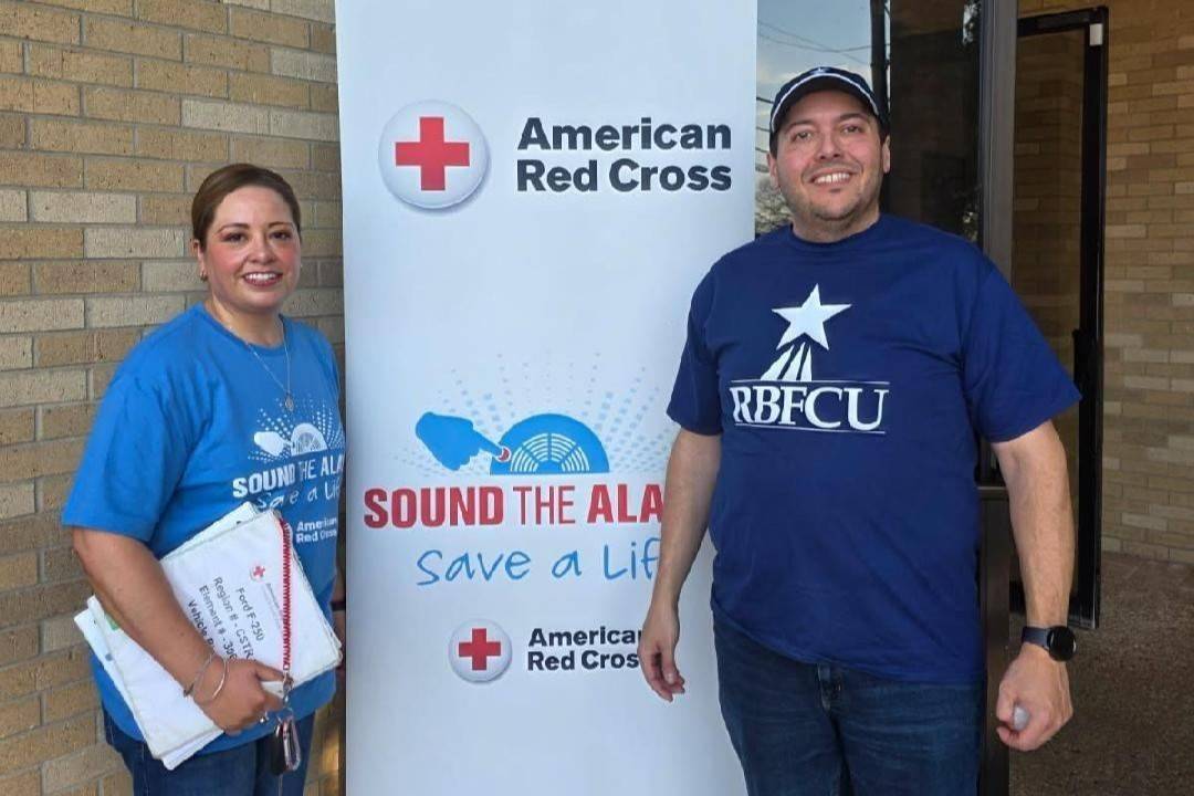 Man and woman stand in front of Sound the Alarm sign