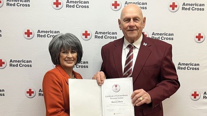 Man and woman standing side by side holding award.