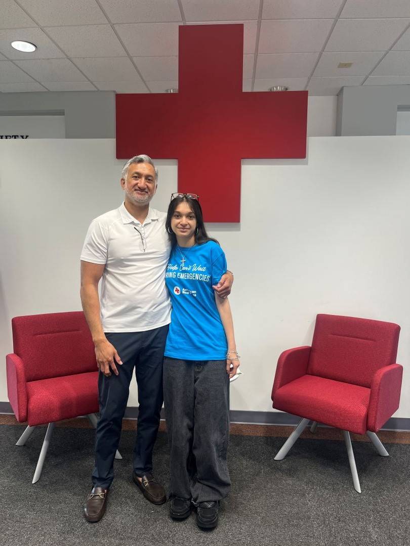 Man and daughter stand in front of Red Cross logo