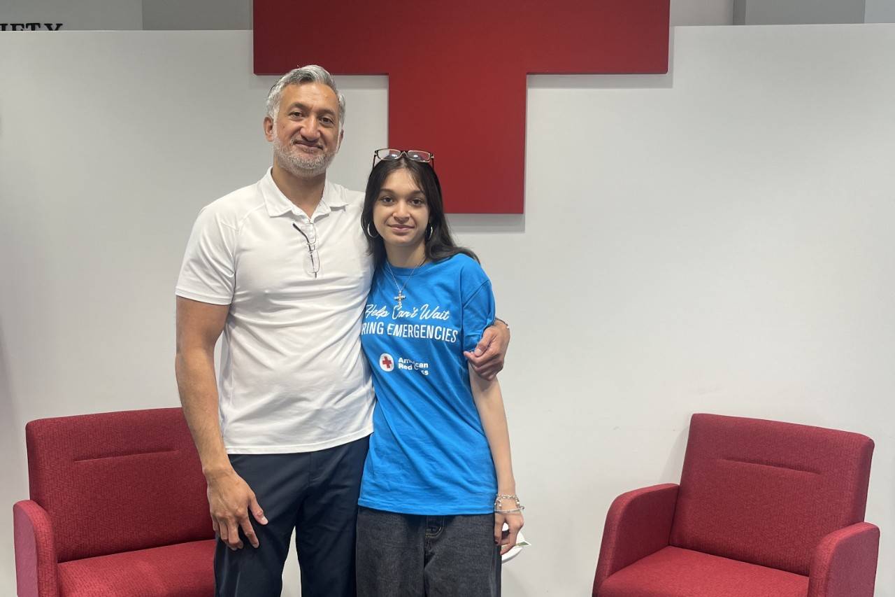 Man and daughter stand in front of Red Cross logo