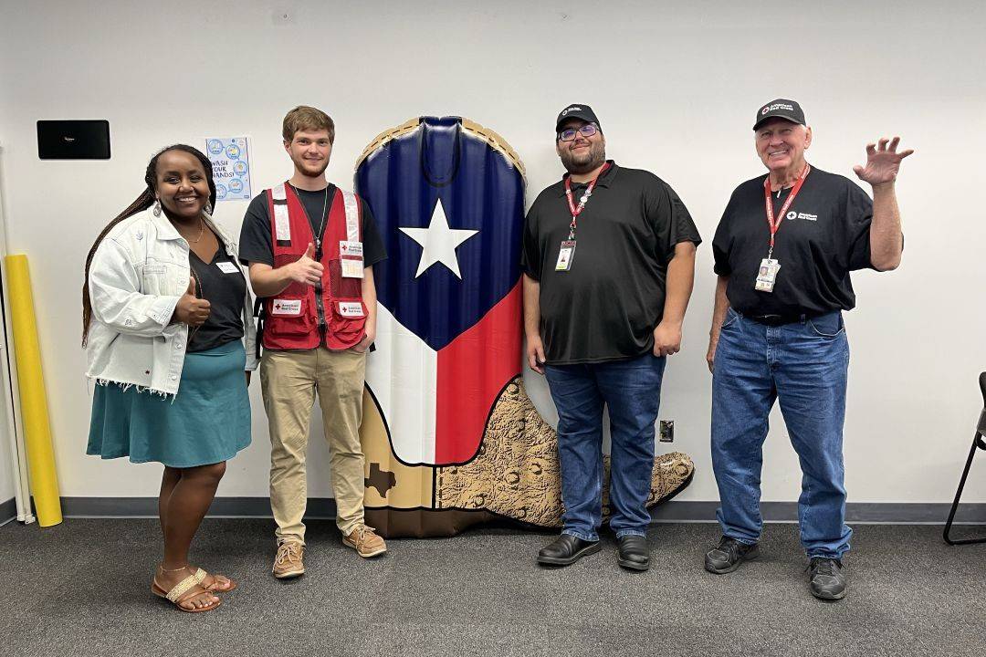 Group of Red Cross volunteers stand in line giving thumbs up 