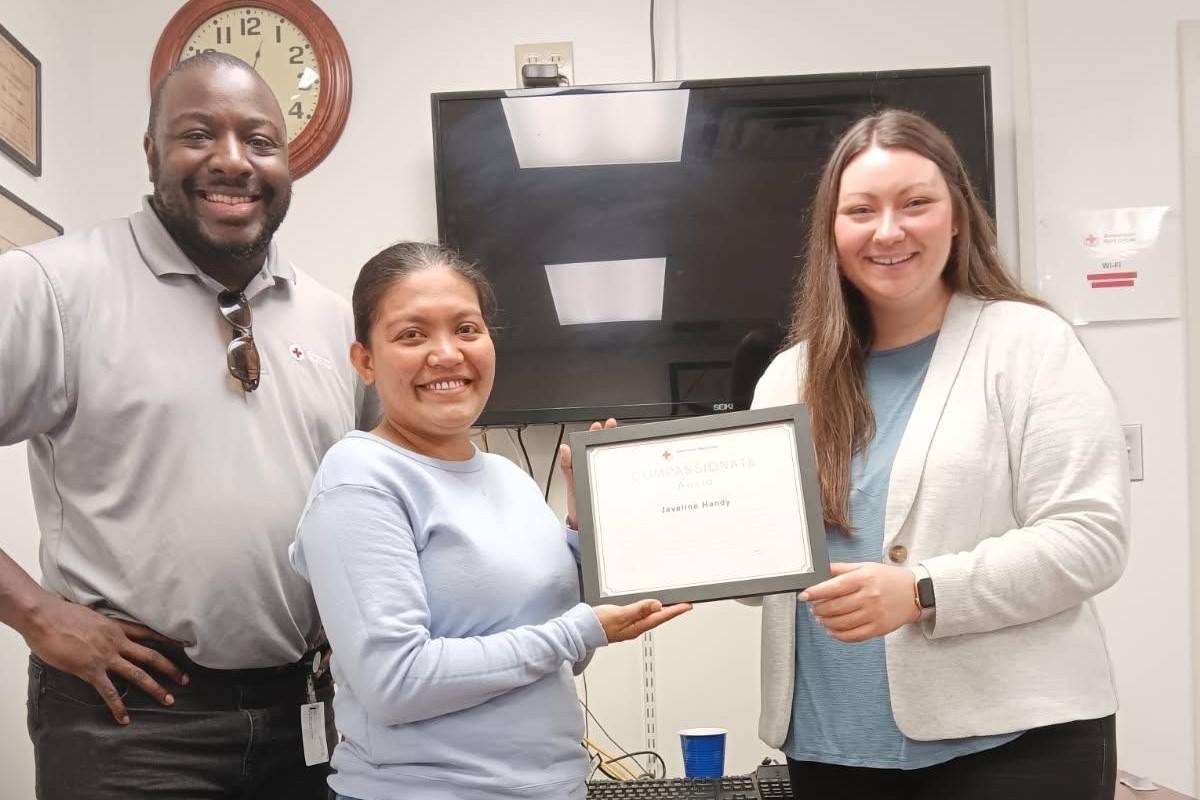 man stands beside two women holding award