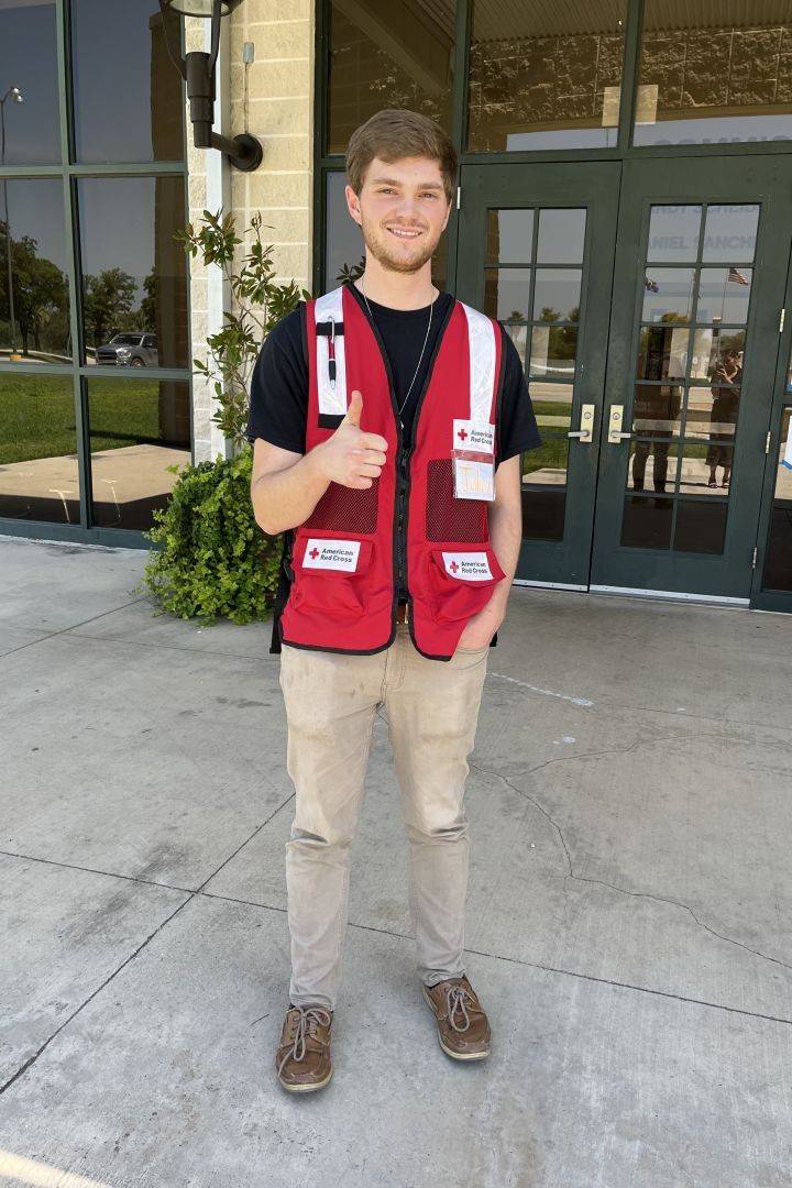 Young man in Red Cross vest gives thumbs up