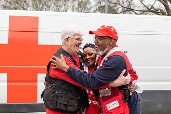 Three Red Cross volunteers hugging each other.