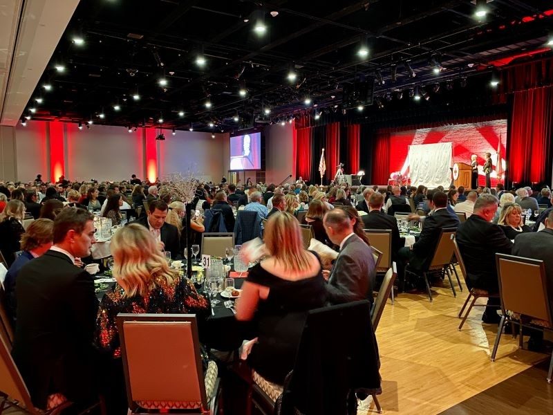 A group of people sitting at tables in a room with red and white curtains