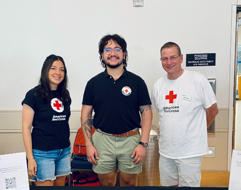 three people standing side by side wearing red cross shirts