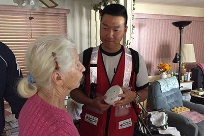 volunteer holding smoke alarm speaking with resident