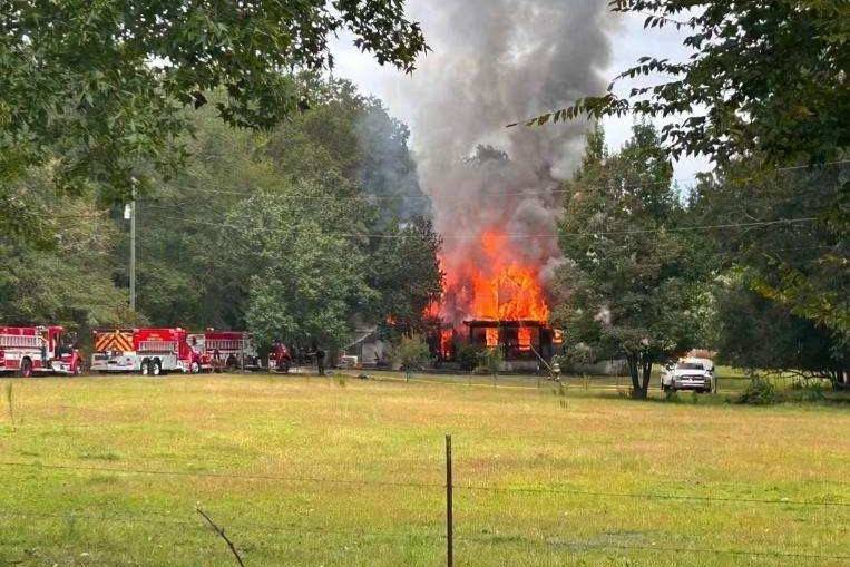 Home engulfed in flames with fire trucks nearby
