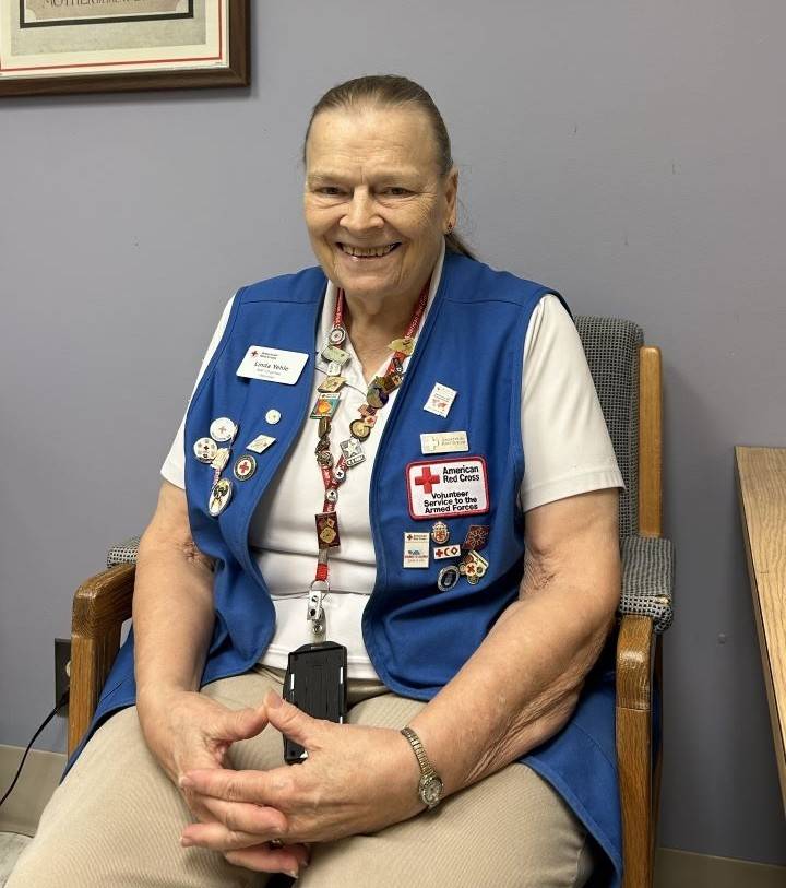 Woman sits wearing Red Cross vest