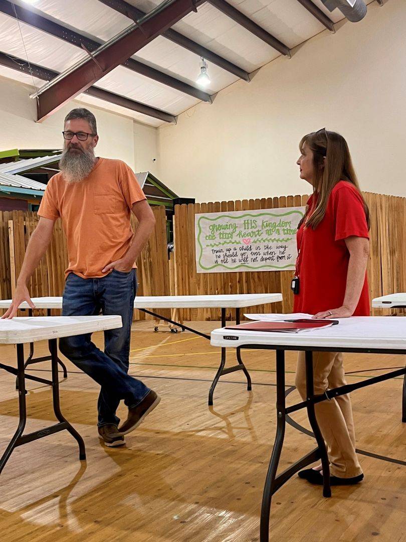 Man and woman stand behind tables