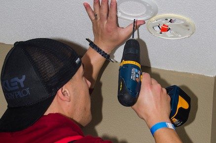 Red Cross volunteer installing smoke alarm in home