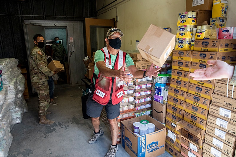 volunteers and U.S. service members loading canned food boxes