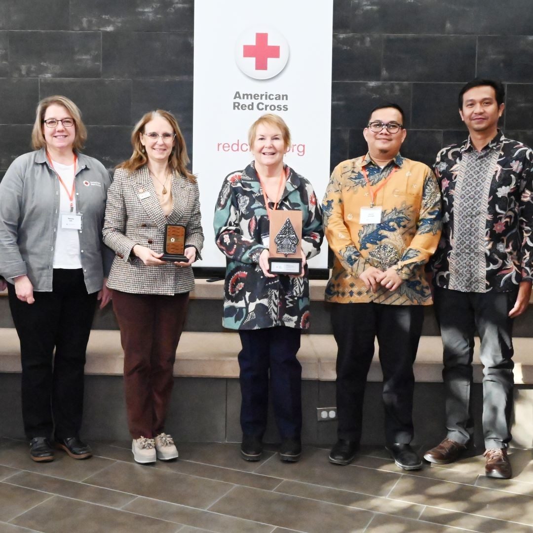 group of people in front of red cross banner