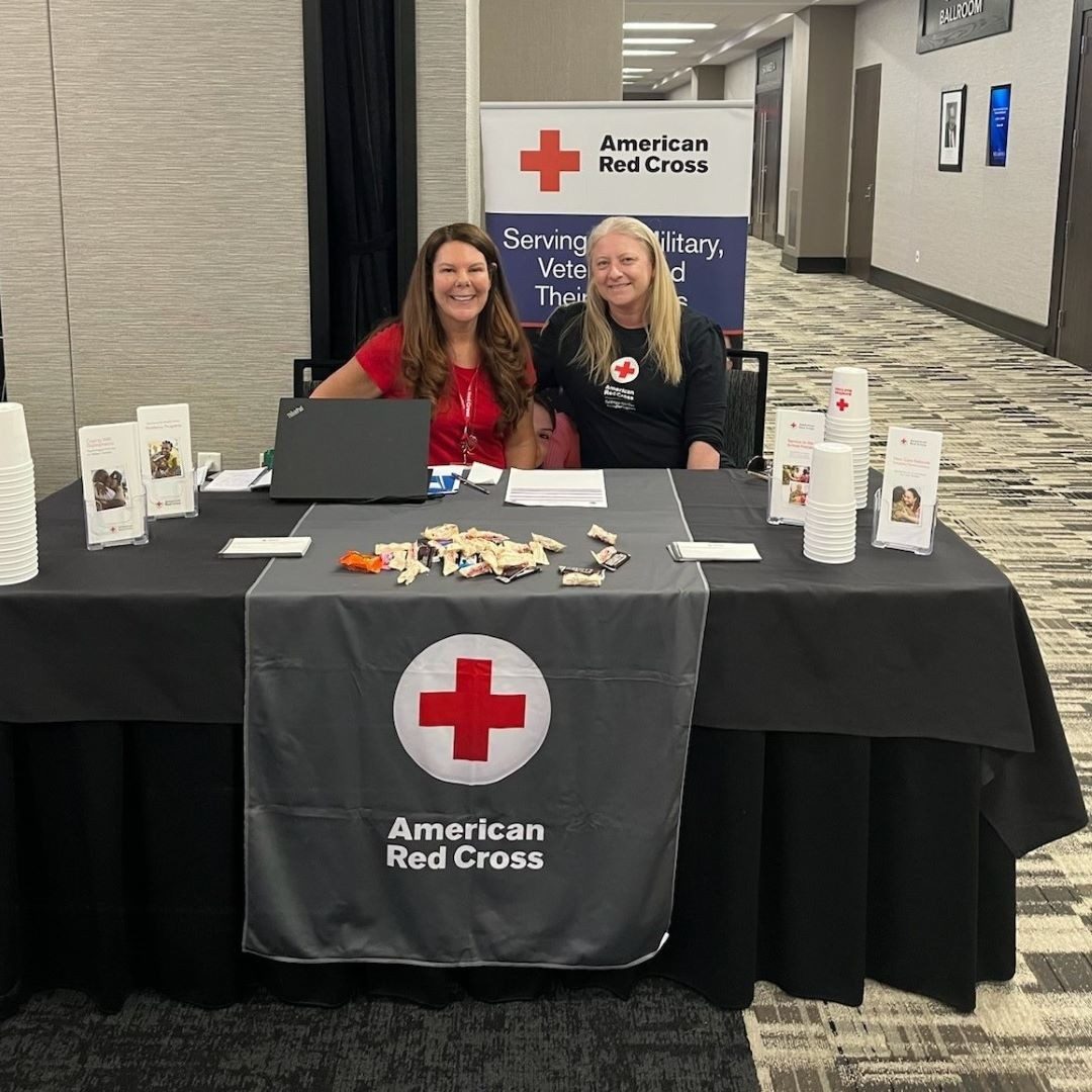 two red cross volunteers behind table