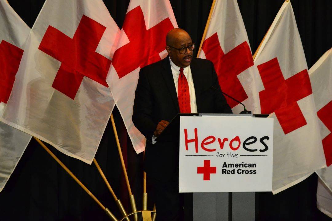 Man speaks from behind podium at Red Cross event