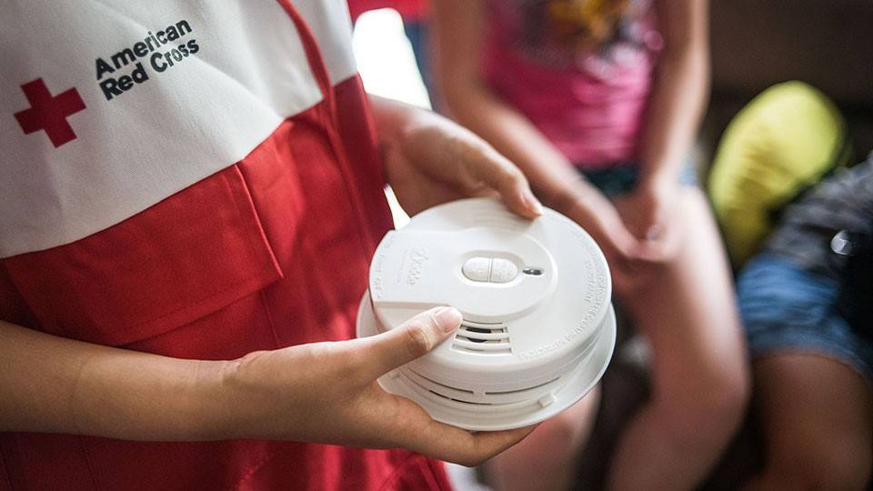 Red Cross volunteer holding smoke alarm