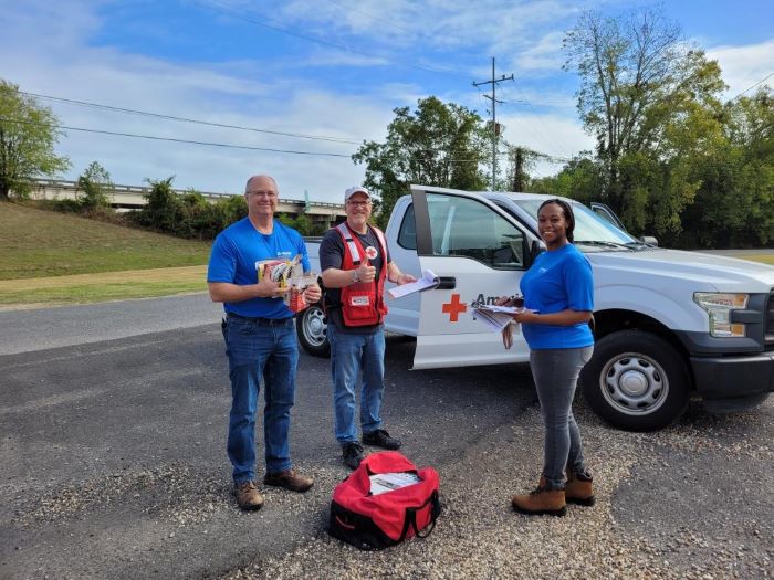 three red cross volunteers standing in front of a truck 