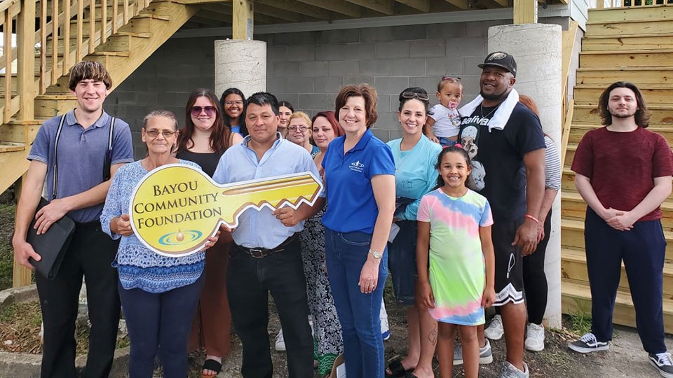 group photo of residents impacted by Hurricane Francine holding a Bayou Community Foundation key shaped sign.