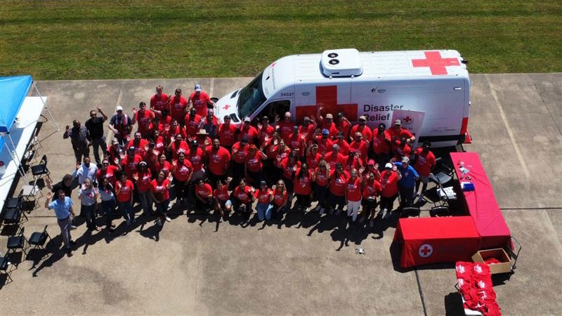 bird's-eye view group photo of the Red Cross disaster teams next to a Red Cross van.