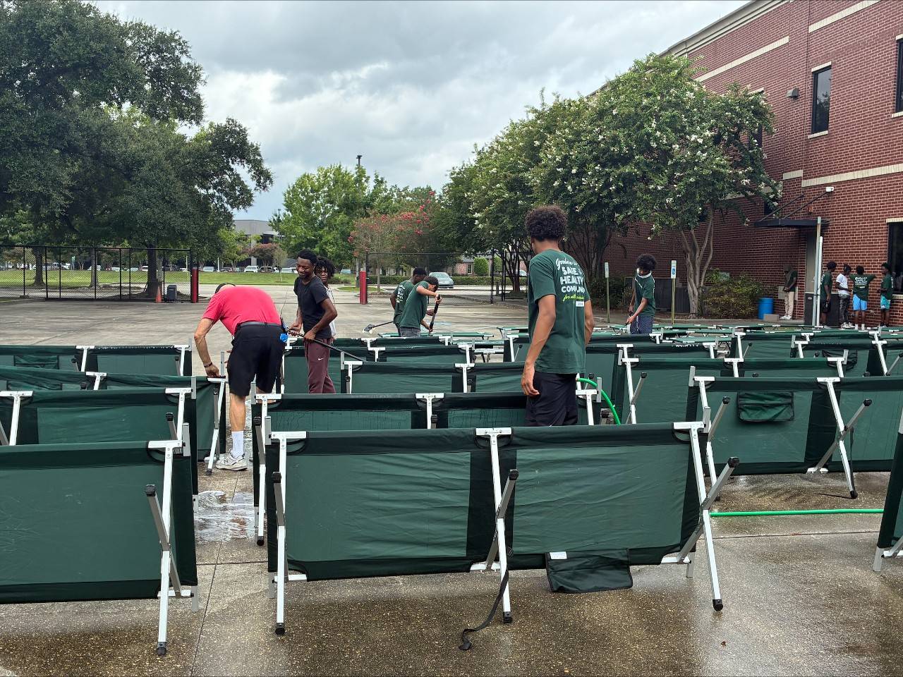 Young men clean cots outside