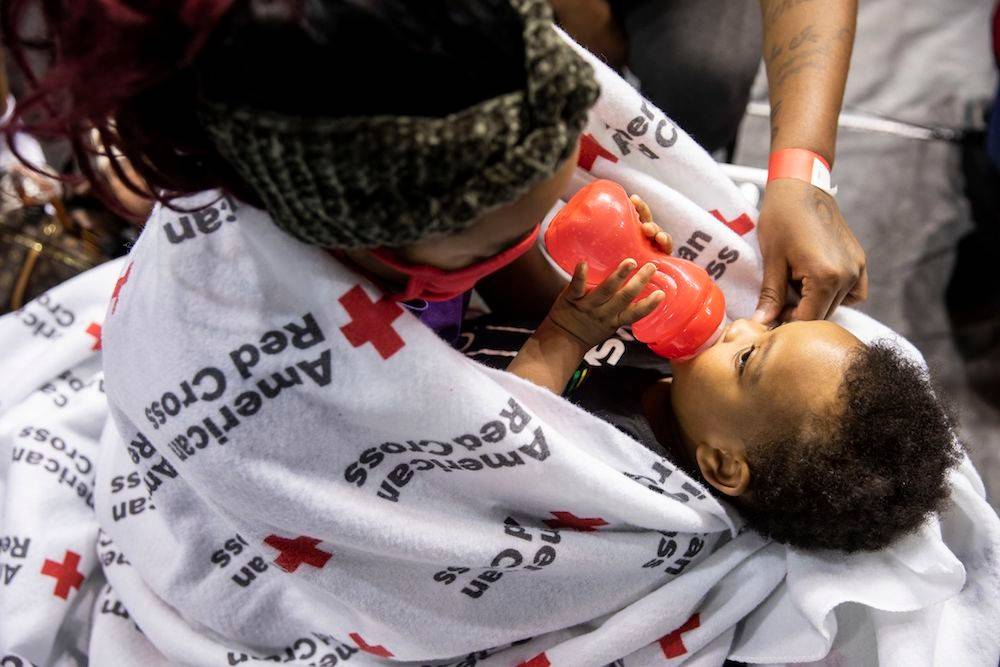 August 29, 2021. Baton Rouge, Louisiana. Ednisha Collins,14, holds brother Ethan Jordan, 1, while her family gets settled at a Red Cross evacuation shelter in Baton Rouge on Sunday August 29, 2021. Ednisha and Ethan’s family are among those seeking refuge from Hurricane Ida, making landfall along the Louisiana coast today as a dangerous Category 4 storm. Ednisha is looking forward to getting back to ninth grade, and activities such as cheerleading and archery. In the meantime, she provides a comforting presence to her baby brother as the family waits for the storm to pass. 

Some 600 Red Cross volunteers are either on the ground or staged to support relief efforts after Ida makes landfall. Across Louisiana and Mississippi, the Red Cross and other organizations have opened dozens of evacuation shelters, offering safe refuge for hundreds of people. The number of open shelters and people staying in them is changing hourly. Photo by Scott Dalton/American Red Cross