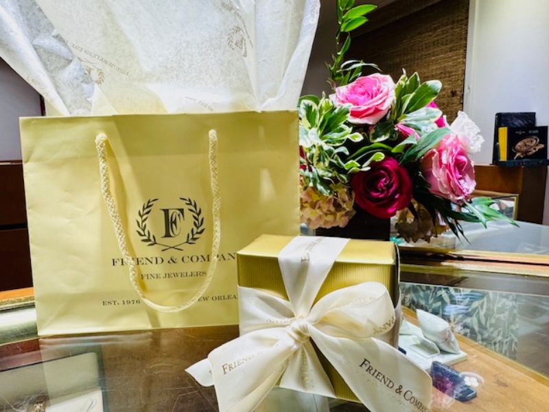 A floral arrangement next to a gift bag.