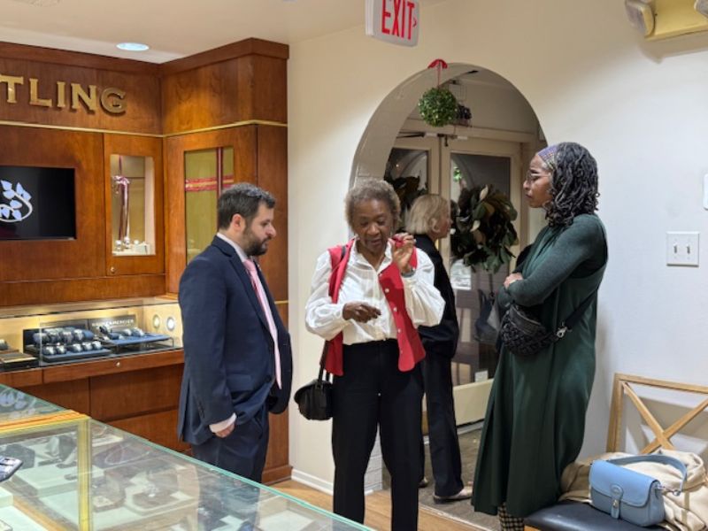 Three people standing next to each other talking.