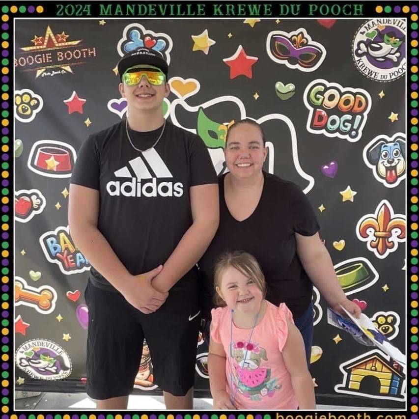 Woman stands with two children in front of photo booth sign
