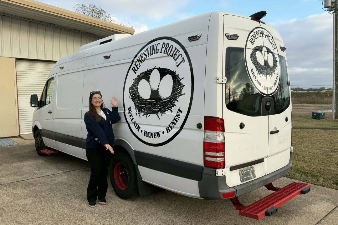 Woman stands in front of van with Renesting logo