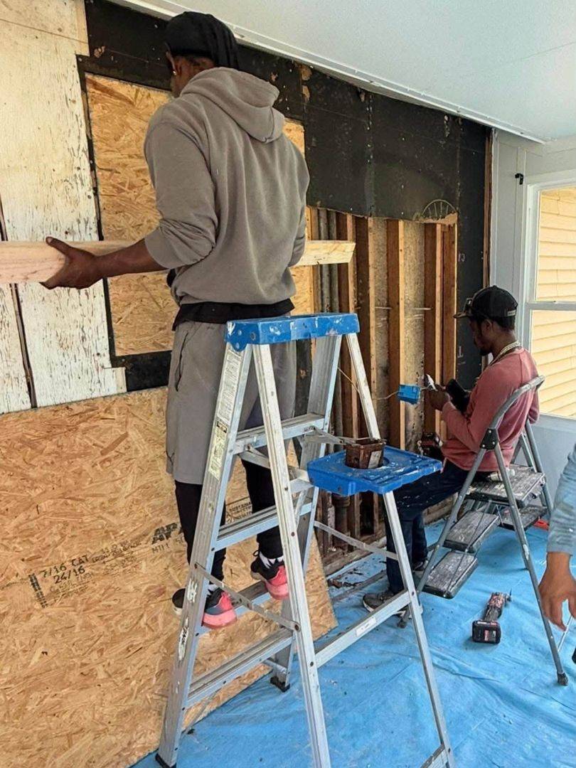 Two men work on construction inside a home