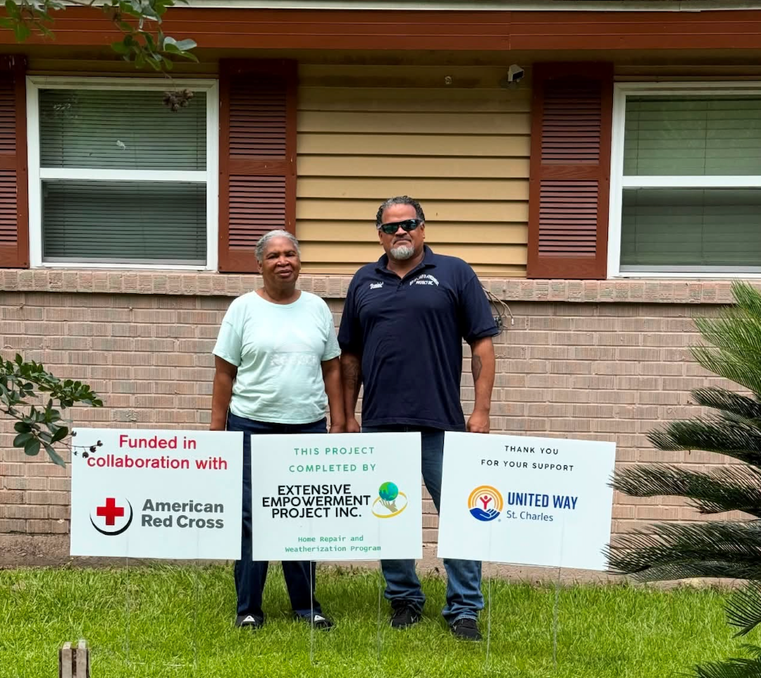 Man and woman stand behind yard signs with nonprofits names and logos on them