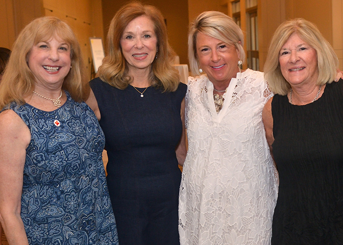 Group of four women next to each other and smiling.