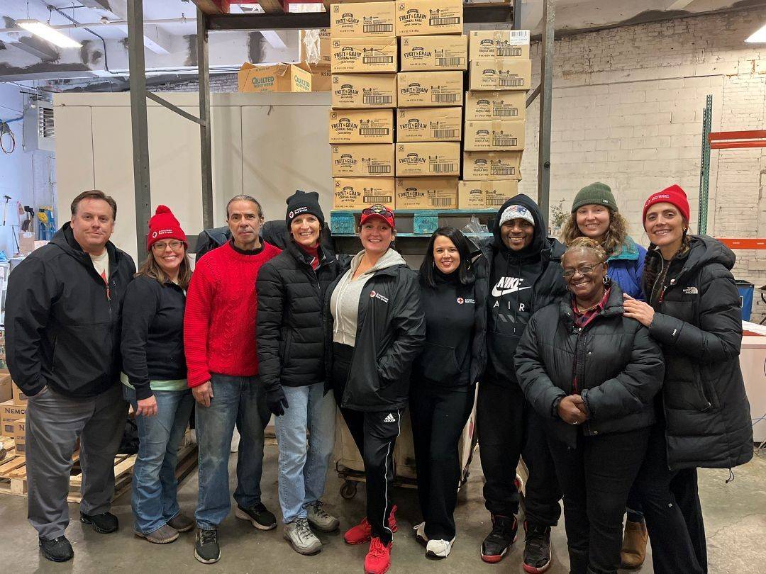 Group of people stand in warehouse in front of boxes