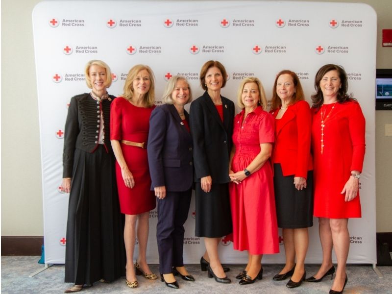 group of heroes breakfast attendees standing in front of red cross backdrop