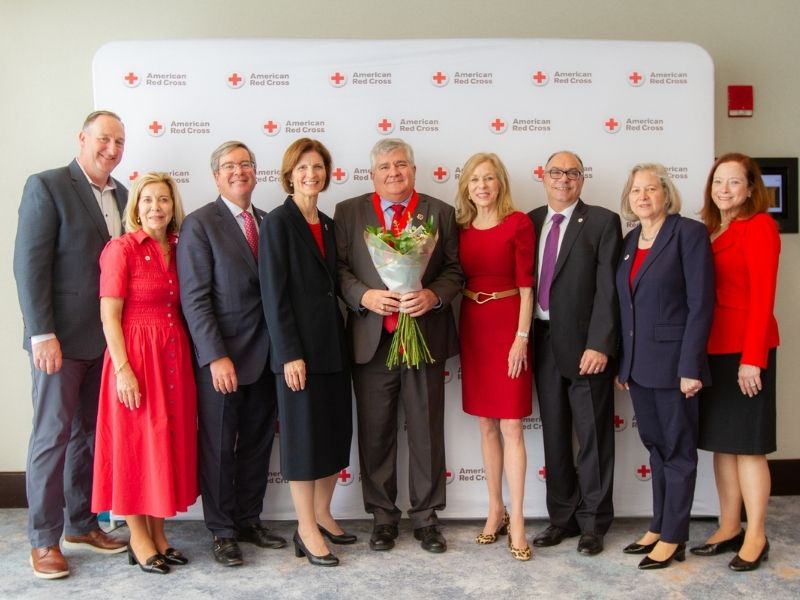 group of heroes breakfast attendees standing in front of red cross backdrop