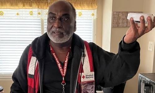 Red Cross holding smoke alarm in hand
