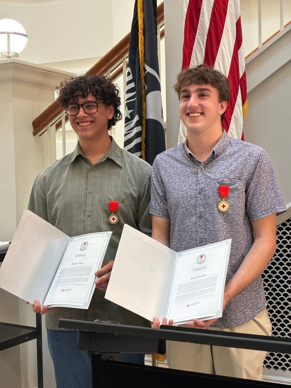 Two young men hold awards from the Red Cross