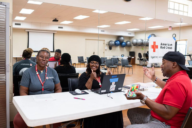 Fred Gilmore being helped by Red Cross volunteers looking at laptop