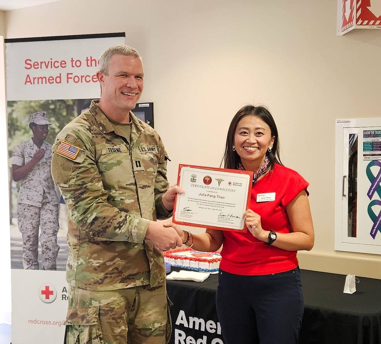 Woman stands next to service member holding certificate