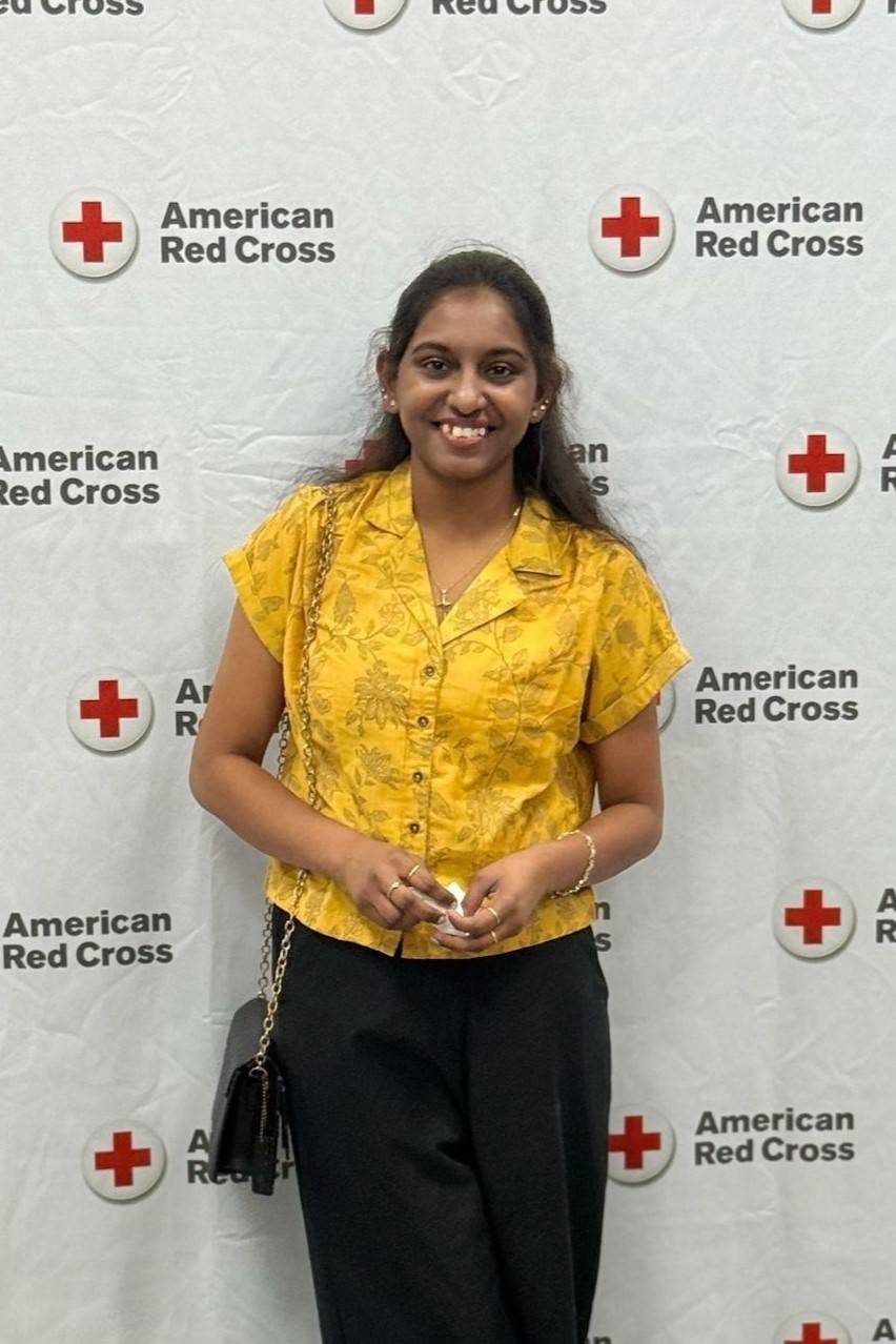 Young woman stands in front of Red Cross banner