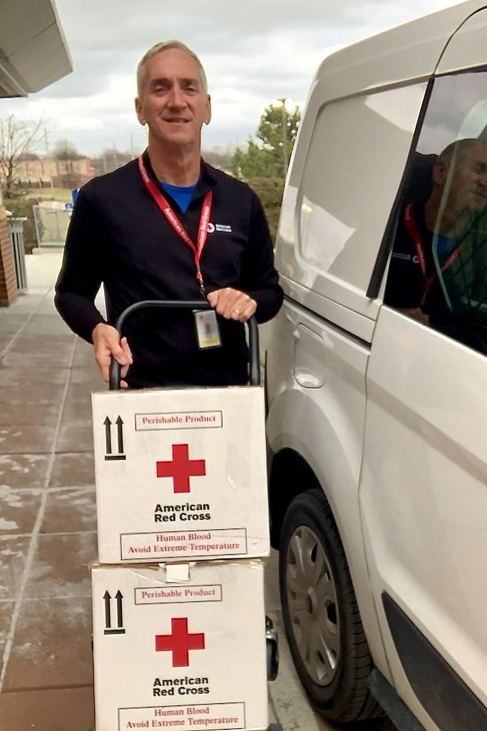 Man wheeling boxes of donated blood to transportation vehicle