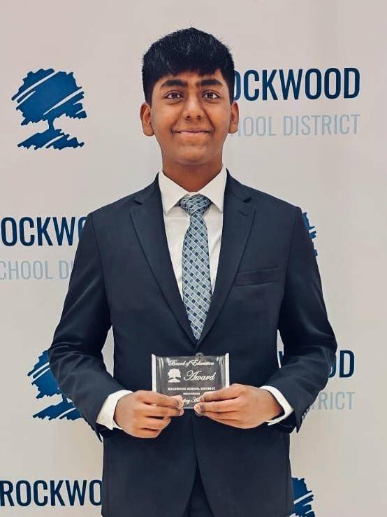 Vignesshwar Viswanathan in suit and tie holding a Red Cross award.