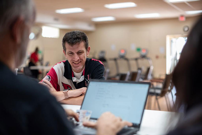 William Fellars being helped by Red Cross volunteer looking at laptop