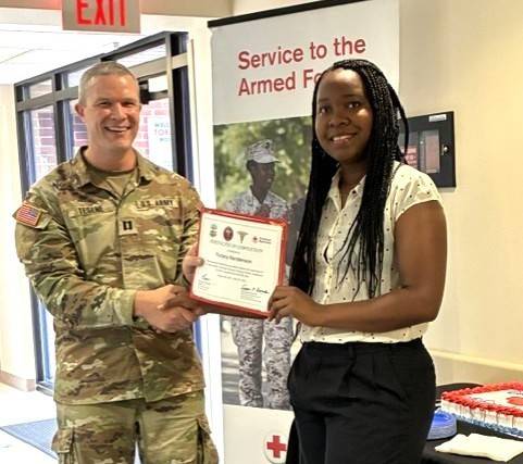 Woman holds certificate while standing next to service member