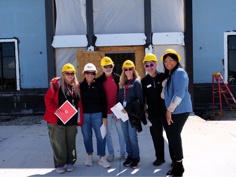 team members in helmets standing in front of building