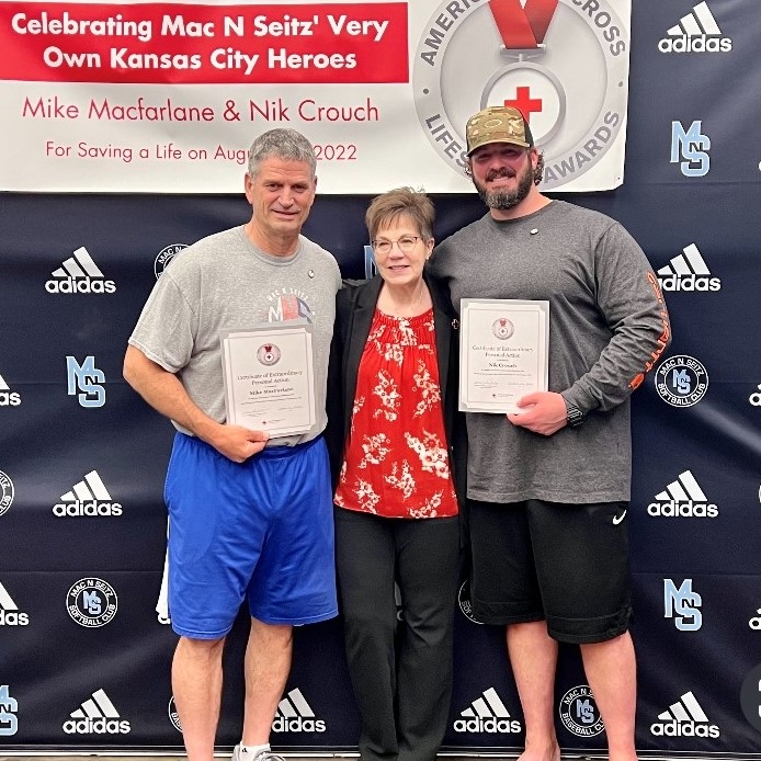 Two recipients holding lifesaver certificates with Red Cross staff member